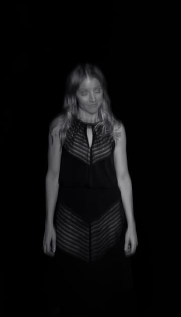 Lisa Apple standing in a black dress against a dark backdrop