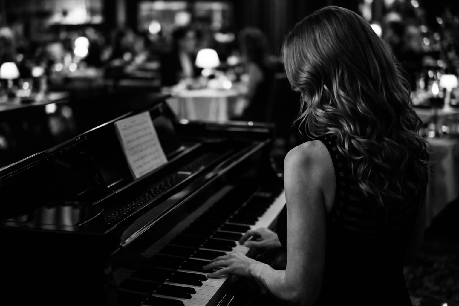 Lisa Apple performing at the piano in a candlelit lounge